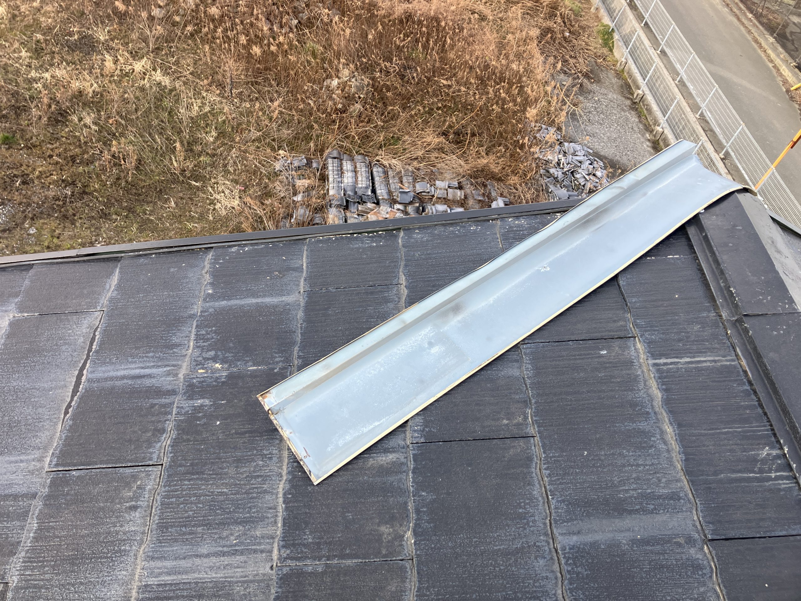 屋根上で板金が大きくめくれ上がっている